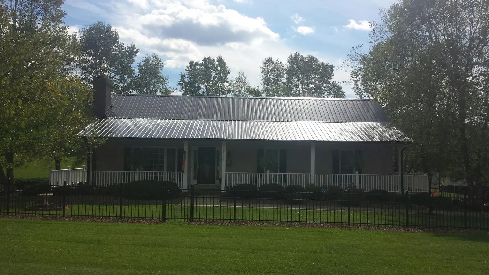 Gray metal roof on a brick ranch with a full width front porch — Gutter Guard Installation work by our crew in Port Washington